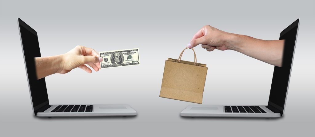 ecommerce-2140604_1920 Person handing another person a bag and money through 2 computer screens