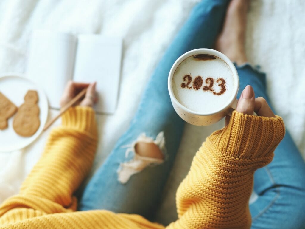 New,Year’s,Goal,Setting,,Number,2023,On,Frothy,Surface,Of Person holding mug that says 2023 on the foam